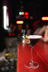 Alcoholic cocktail decorated with dried orange and mint. Night club, close-up