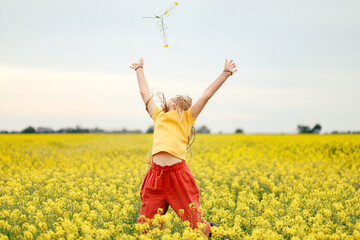 Pretty long haired girl playing in vibrant canola field in full bloom