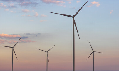 Windmills for electric power production at sunset.