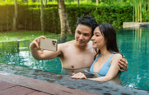 happy couple taking selfie photo at edge of swimming pool