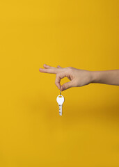 Man hand holding key on yellow background. Real estate deal