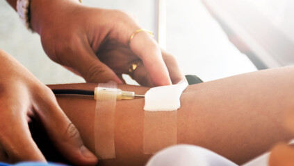 Medical volunteer presses gauze with his fingers to tightly cover the wound on the arm of a donor who donated blood. Soft and selective focus.