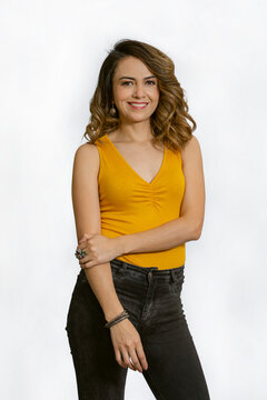 Young woman smiling standing casually dressed in yellow blouse and black jean isolated on white background
