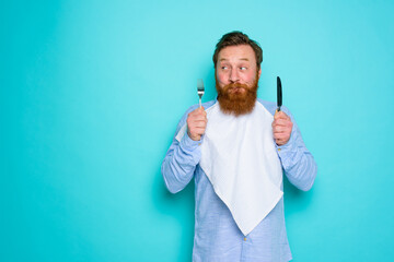 Man with tattoos is ready to eat with cutlery in hand