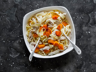 Fettuccine with chicken and baked pumpkin in cream sauce on a dark background, top view