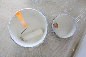 Paint bucket with clear protect plastic in empty room of new house. Top view.