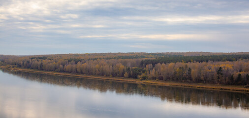 Beautiful, wide river autumn among the woods. Calm and quiet place with autumn colors. In the middle of the river island. View from the top to the distance