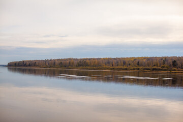 Beautiful, wide river autumn among the woods. Calm and quiet place with autumn colors. In the middle of the river island. View from the top to the distance
