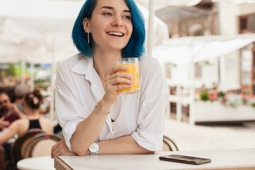 Stylish young woman waiting on a restaurant terrace, feeling happy on a summer day