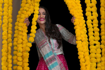 A woman dressed in traditional wear looking through festive flower garlands decoration.