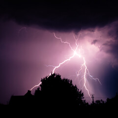 Multiple lightning strikes painting the sky purple on a summer evening during a thunderstorm