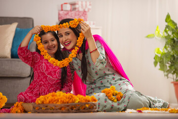 Mother and daughter together enjoying with flower garland on festival