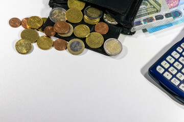 European money with black wallet on white desk as white background with different euro coins and euro bank notes with calculator for financial management and income business plans for tax calculation