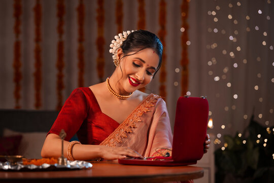 A beautiful woman touching the ornament in gold jewellery box amidst diwali decoration, lights and a pooja thali.