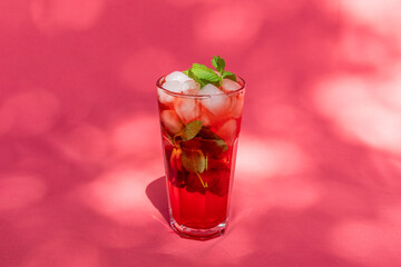 Summer Berry fruit iced tea with ice cubes against rose abstract background.