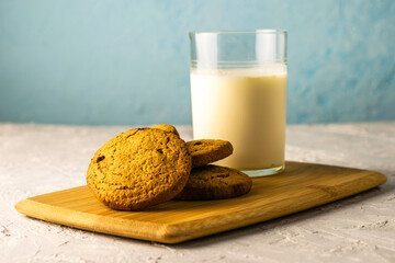 oatmeal cookies and a glass of milk on a wooden cutting board on the table