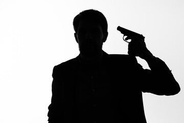 The man in a suit gun in the hands of the emotions silhouette posing studio