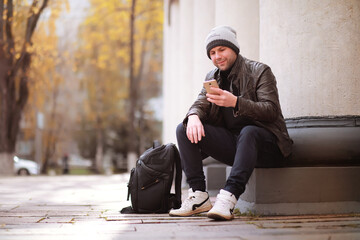 Autumn concept. A man walks through the city. Autumn leaves on the footpath. 