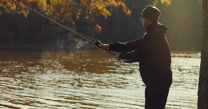 fisherman casting spinning rod into the lake on sunny autumn day. lure fishing
