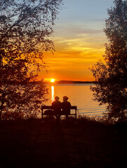 Naklejka na ściany i meble Couple sitting on a bench in summer sunset