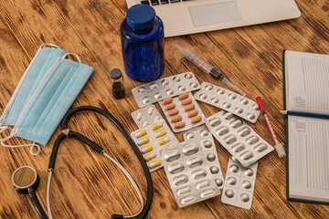 Stethoscope many pill mask with syringes standing spread out on a wooden table