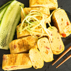 Japanese omelet - tamagoyaki rolls with cucumbers close-up, top view