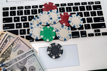 poker chips with banknotes placed on a laptop keyboard