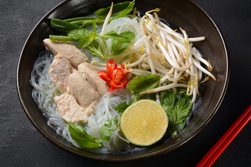 Pho Ga soup  with chicken, rice noodles and fresh herbs in a bowl. Vietnamese cuisine