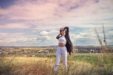 Happy young pretty woman enjoying the landscape near green field