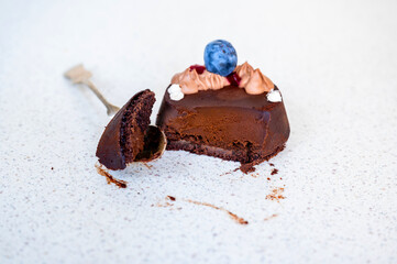 Cut chocolate dessert (fondant) with blueberry and cream, piece on spoon.