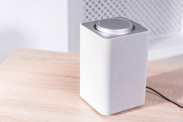 smart speaker on the table in the room, gadget in the apartment close-up, selective focus, tinted image, bright sunlight from the window