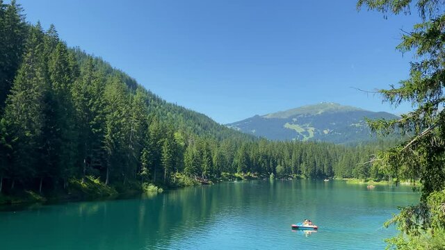 Lake Cauma in Flims, Canton of Grisons in Switzerland. A Trent boat with a family is sailing across the lake. A very famous and popular destination in Switzerland