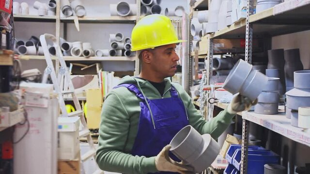 Plumber in protective helmet and overalls selects plastic pipes in a hardware store. High quality FullHD footage