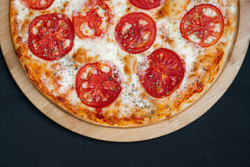Pizza Margherita with Tomatoes on black stone background, top view.