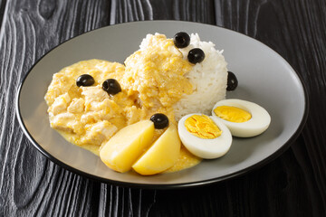 Ají de Gallina in a creamy sauce with parmesan, pepper and onion, served with rice and boiled eggs close-up in a plate on the table. horizontal