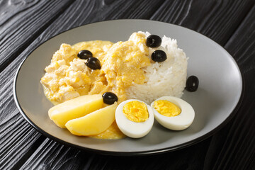 Peruvian Aji de Gallina made with ají peppers, chicken, parmesan and a cream sauce with rice in the plate on the table. Horizontal