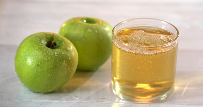 Fresh organic raditional apple wine in the city of Frankfurt in Hesse. A jug of wine is on an old wooden table in the garden, around it are apples.