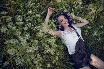 portrait of a teenage girl with purple hair and an earring in her nose lying in the grass