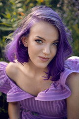 Fototapeta premium teenage girl with dyed purple hair and a nose piercing in the grass with a bouquet