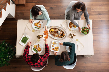 Top view of happy family having Christmas dinner together. Passing plates along. Serving food....