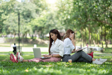 Happy asian university sitting outside on campus. two girl working and studying together with...