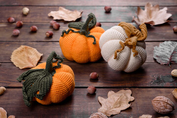 Handcraft autumn still life: knitted pumpkins and leaves on a wooden background