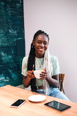 Young black girl drinking her coffee at cafe.