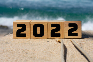 wooden cube written 2022 on the beach sand.