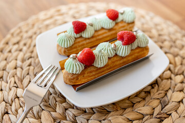 Beautiful delicious eclairs on the table in a plate. Delicious pastries close-up. Table setting