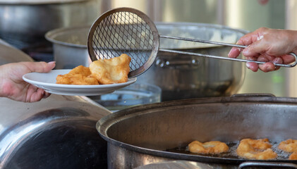 Dough donuts are fried in oil. A cafe
