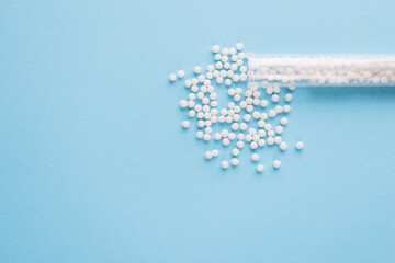 Homeopathic pills and plastic container on a blue background. Homeopathic medicine