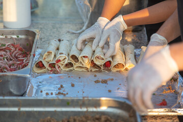 The cook wraps meat and tomatoes