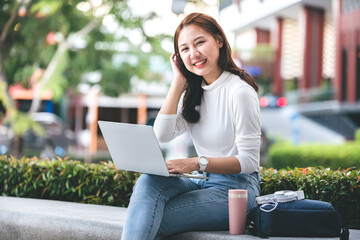 Female college students sit happily working outdoors after school. On campus at sunset with warm light