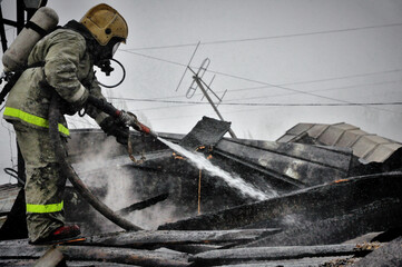 Firefighters extinguish a fire on the roof of a house on a frosty winter day